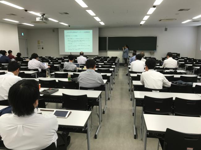 ワークショップにて学生委員会の倉田委員長からの報告を聞く学科教員